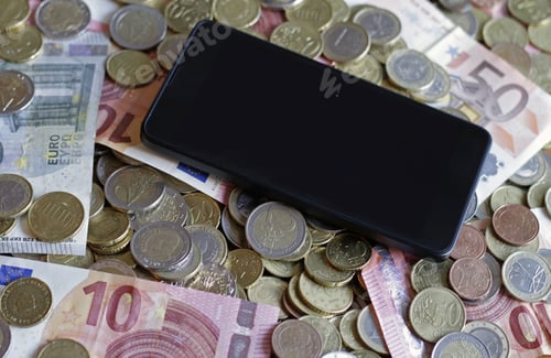 Preview: Overhead shot of a smartphone on coins and bills