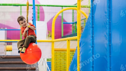 Preview: A cheerful little boy is playing in the children's entertainment center on the playground.