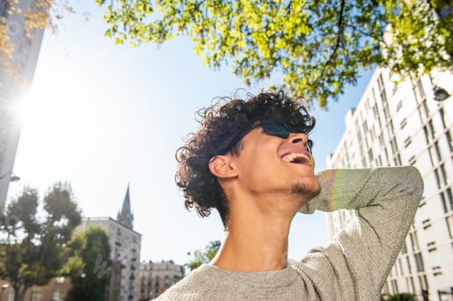 Preview: Close up young man laughing with sunglasses and hand behind head