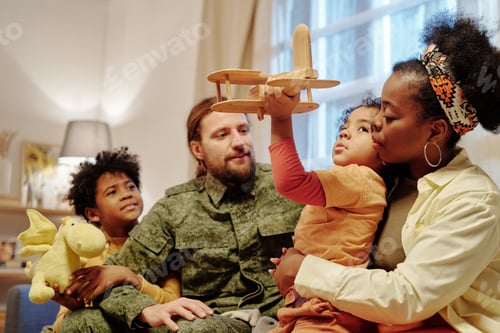 Vista previa: Young African American woman embracing her son with toy airplane