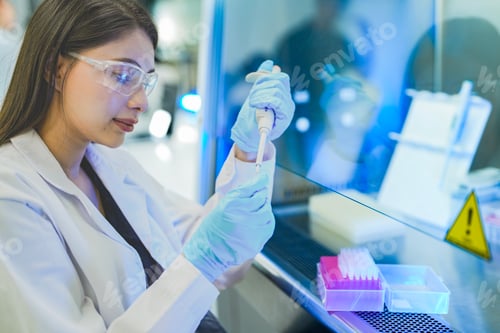 Preview: A focused Asian scientist uses a micropipette to transfer liquid samples