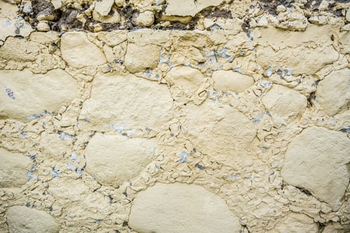 Preview: gray wall surface of old stones with plaster in cracks.