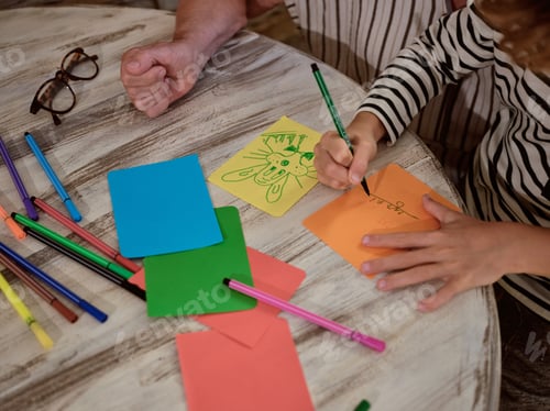 Preview: Unrecognizable kid drawing near grandparent