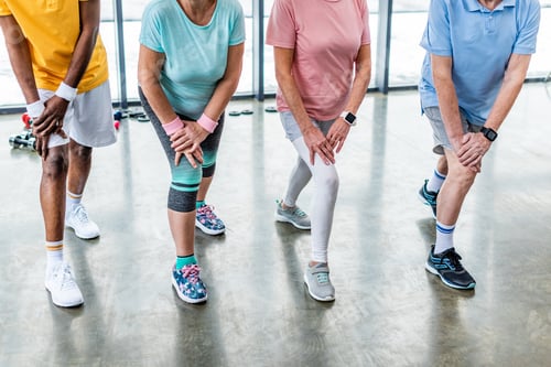 Preview: partial view of senior sportspeople synchronous stretching at gym