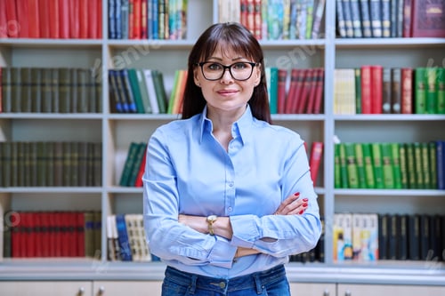 Preview: Portrait of confident female teacher with crossed arms inside library