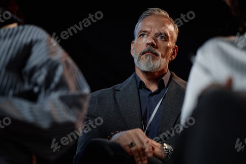 Preview: Focused Senior Man in Suit Attending Business Conference against Black