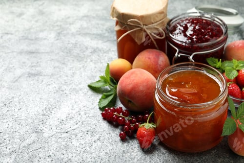Preview: Jars with different jams and fresh fruits on grey table. Space for text
