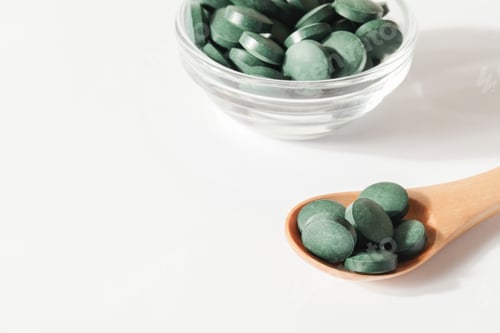 Preview: natural additives and superfood. green spirulina algae pills in spoon and glass bowl