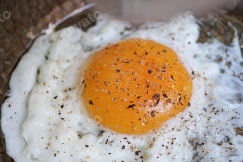 Preview: Brightly cooked egg with seasonings on a textured plate