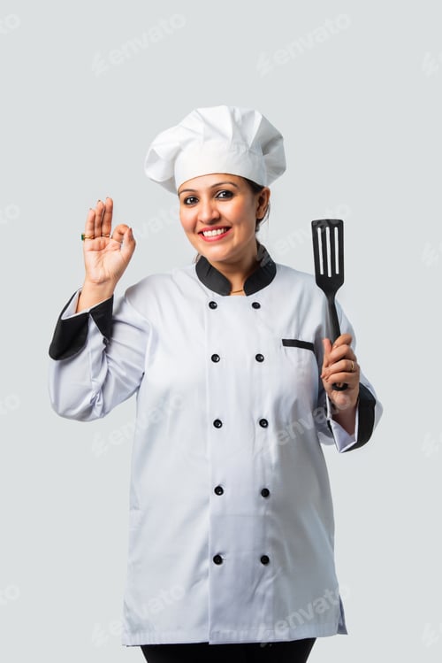 Preview: Young Indian asian female chef smiling with spatula - professional culinary expert