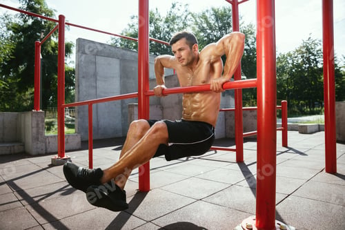 Preview: Young muscular man while doing his workout outside at playground