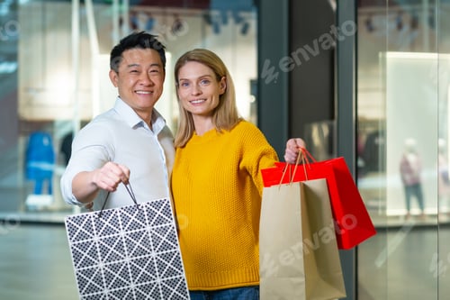 Preview: Young asian man and woman couple in supermarket shopping, looking at camera