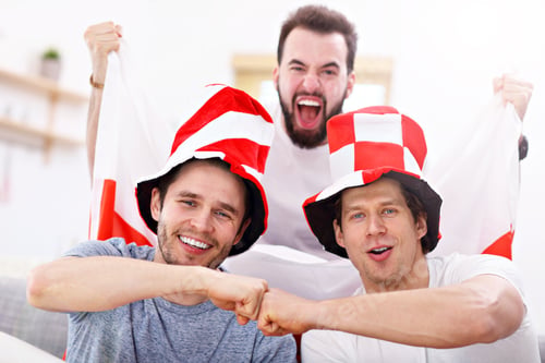 Preview: Happy male friends cheering and watching sports on tv