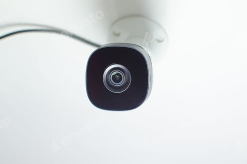 Preview: Close-up of a security camera mounted on a wall in a modern office, ready to be used