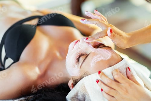 Preview: Spa mask. Cosmetologist smears cosmetic mask on the face of woman