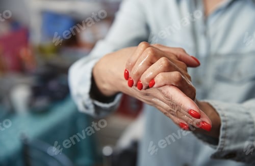 Preview: Woman Applying Cream to Hands with Red Nails