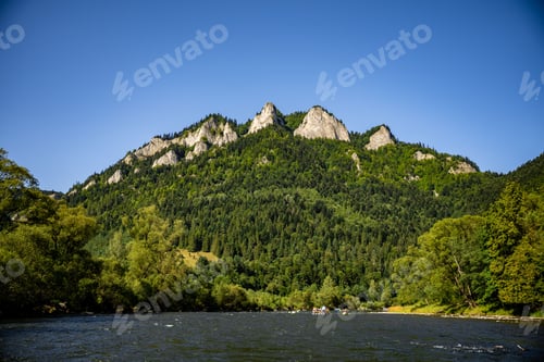 Preview: Beautiful view of a mountain and forest with group of people boating on a river