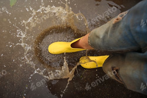 Preview: Crop person in rubber boots playing in puddle