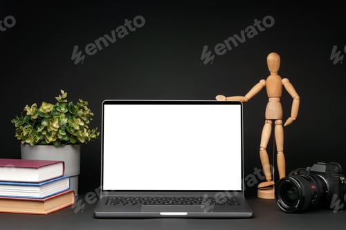 Visualização: Laptop aberto com manequim de madeira na mesa contra fundo preto