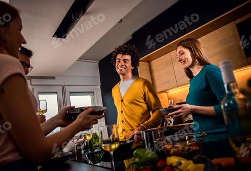 Preview: Group of friends having dinner party at home drinking wine and eating vegetarian food.