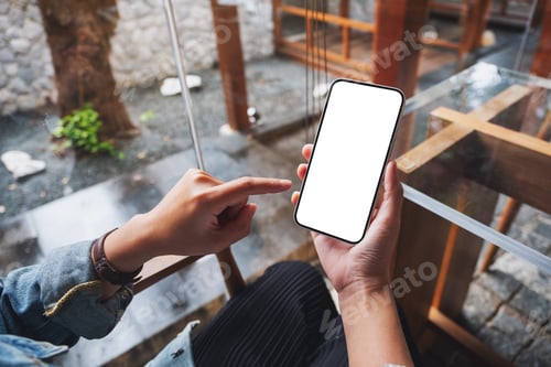 Preview: Mockup image of a woman holding and pointing finger at mobile phone