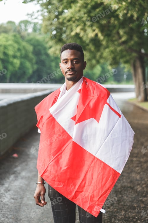 Preview: Handsome Afro American man with Canadian flag on his shoulders outdoor