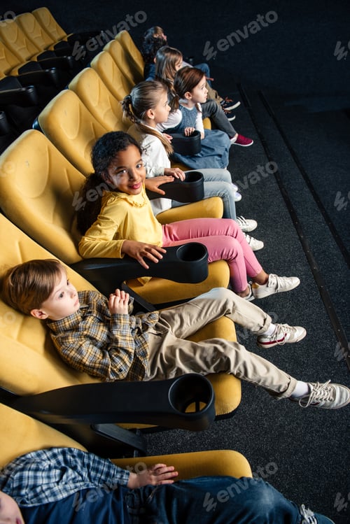 Preview: smiling multiethnic friends watching movie in cinema together