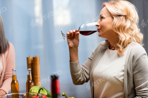 Preview: side view of attractive woman drinking wine from wine glass