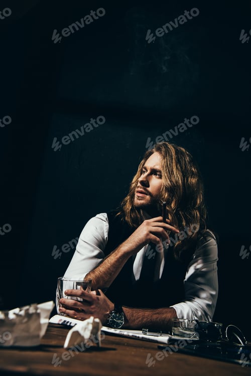 Preview: Handsome stylish young man drinking alcohol and smoking cigar while sitting at table