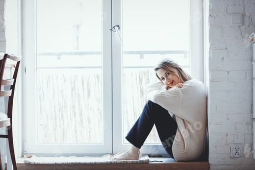 Preview: girl dressed in a sweater is sitting at the threshold