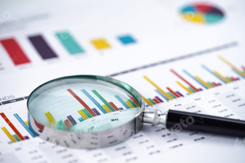 Preview: Magnifying glass on charts graphs spreadsheet paper.