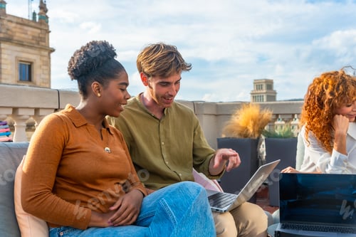 Preview: Coworkers collaborating on laptops during rooftop meeting