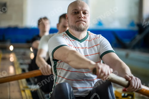 Preview: Focused forced rowing athletes train intensely on rowing simulator during synchronized team workout