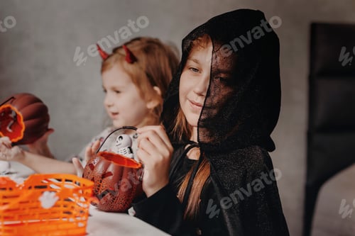 Preview: Two Children with Halloween Candy Buckets at Home