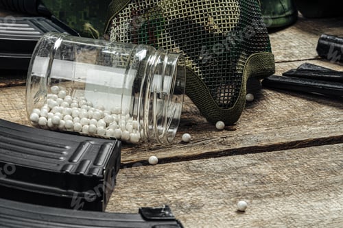 Preview: Close up of airsoft gun magazine and airsoft balls on wooden background
