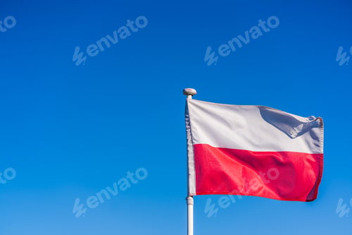 Preview: Closeup of the Polish Flag on a flagpole under the sunlight and a blue sky