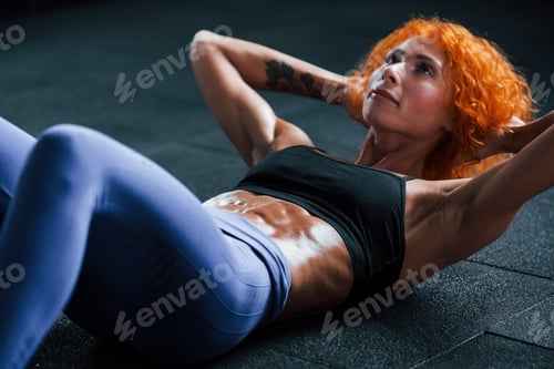 Preview: Sporty redhead girl have fitness day in gym at daytime. Muscular body type