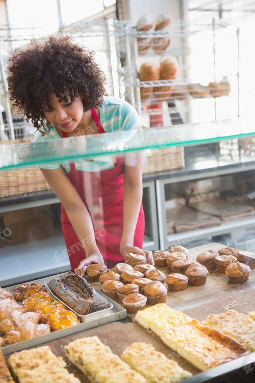 Preview: Smiling employee moving over the pastry at the bakery