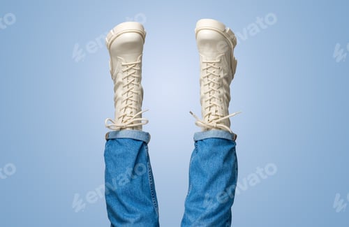 Preview: Female legs in white combat boots and blue jeans upside down on blue background