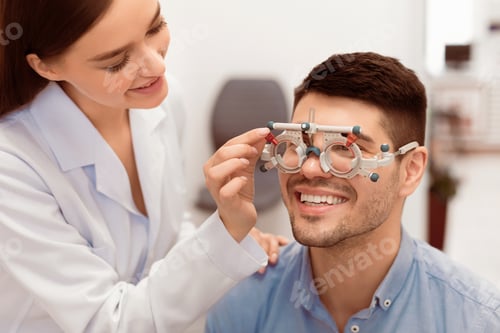Preview: Optometrist checking patients vision with trial frame at clinic