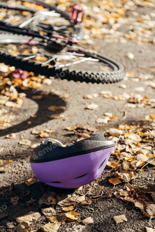Preview: Purple helmet lies abandoned on the pavement beside a toppled bicycle, evidence of a sudden fall.