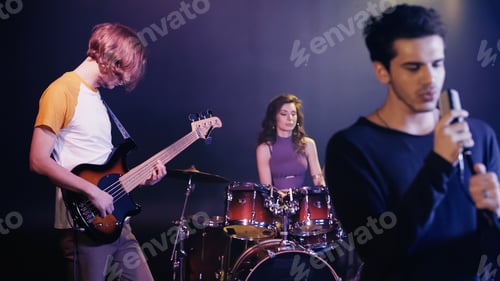 Preview: blurred young singer performing song with music band on stage
