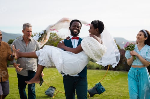 Preview: Portrait of happy african american couple carrying during wedding