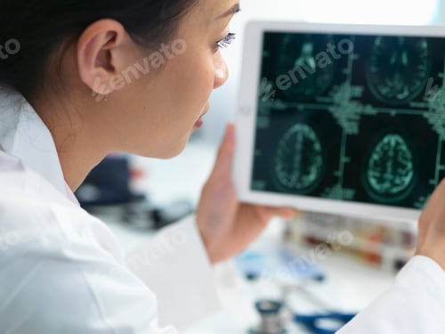 Preview: Doctor viewing CT scan result of brain on digital tablet for abnormalities