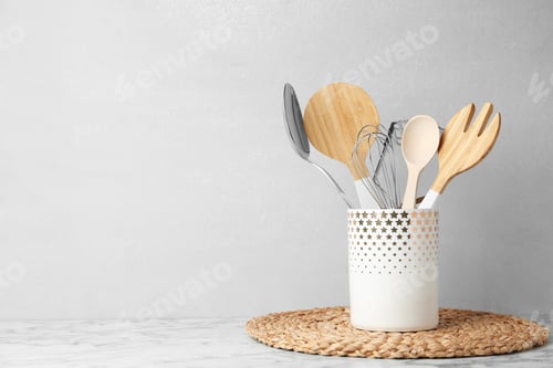 Preview: Different kitchen utensils on table against light background. Space for text