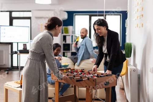 Preview: Cheerful colleagues enjoying game at foosball table