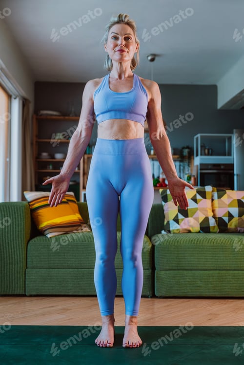 Preview: Fit mature woman practicing yoga in her living room,