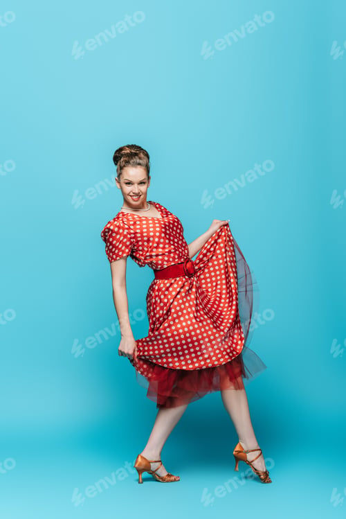 Preview: happy, cheerful dancer looking at camera while dancing boogie-woogie on blue background