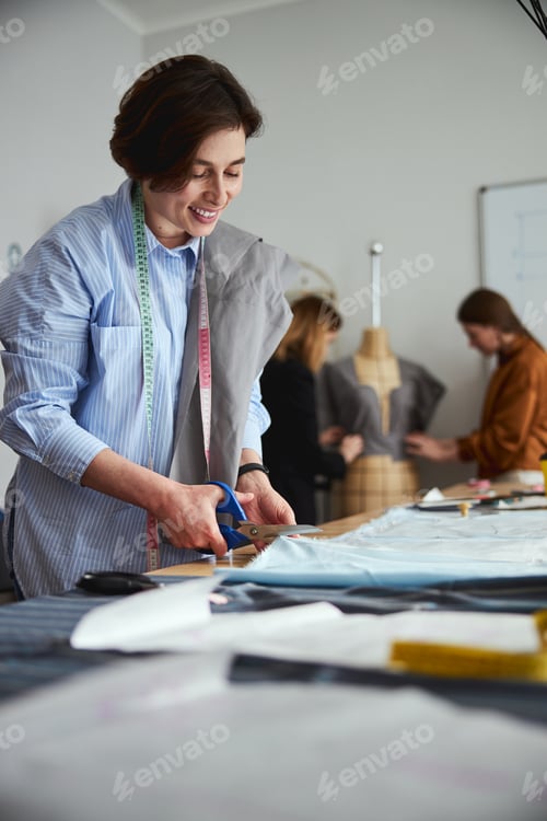 Preview: Dress designer cutting a fabric sheet with scissors