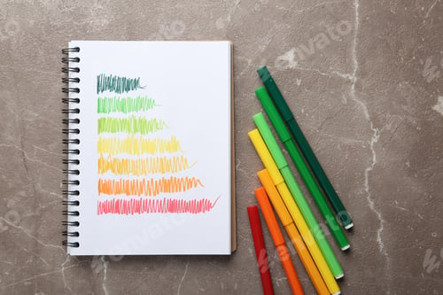 Preview: Notebook with colorful bars and markers on grey background, flat lay. Energy efficiency rating chart
